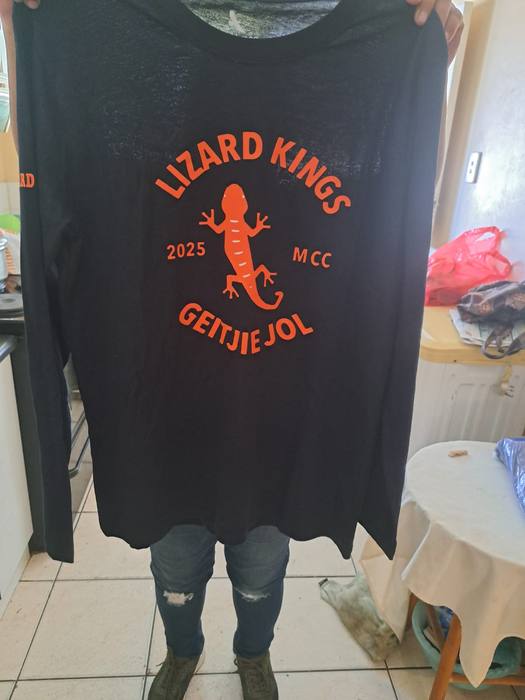 Black long-sleeve club shirt printed Lizard Kings MCC 2025 Geitjie Jol around an orange lizard