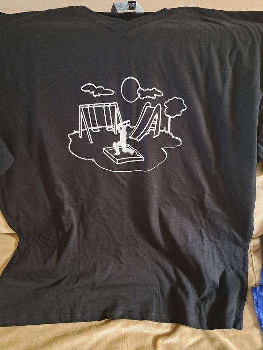 Black t-shirt printed with a white line drawing of a playground with swings, a slide and a sandpit