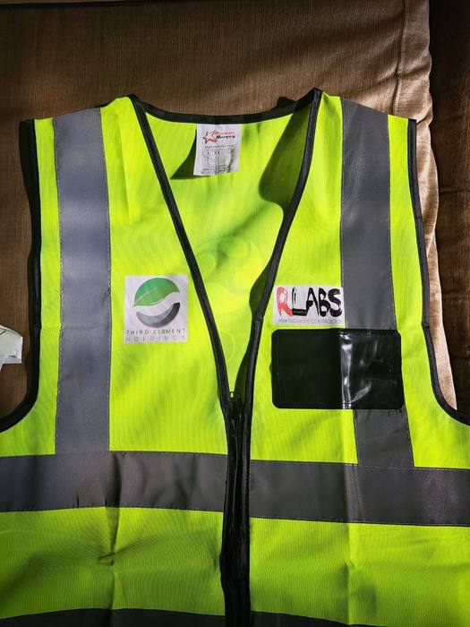 Front of a high-visibility work vest printed with Third Element Holdings and R Labs logos beside a clear ID pocket